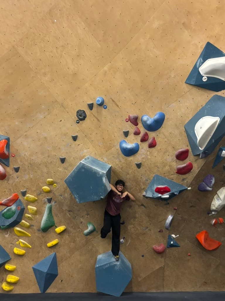 Erik resting against a volume on an indoor bouldering wall
