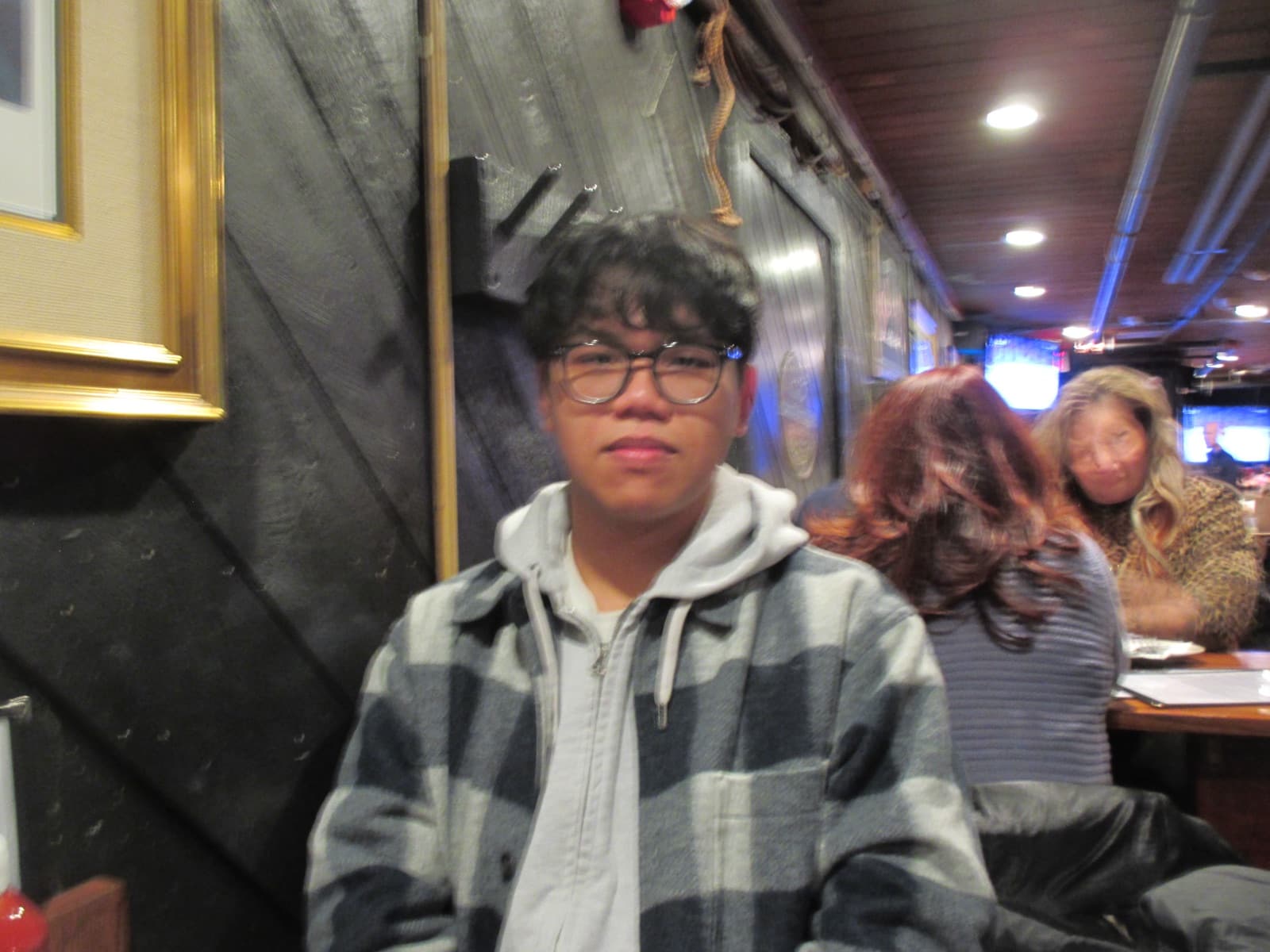 Erik in a plaid flannel jacket at a wood-paneled restaurant